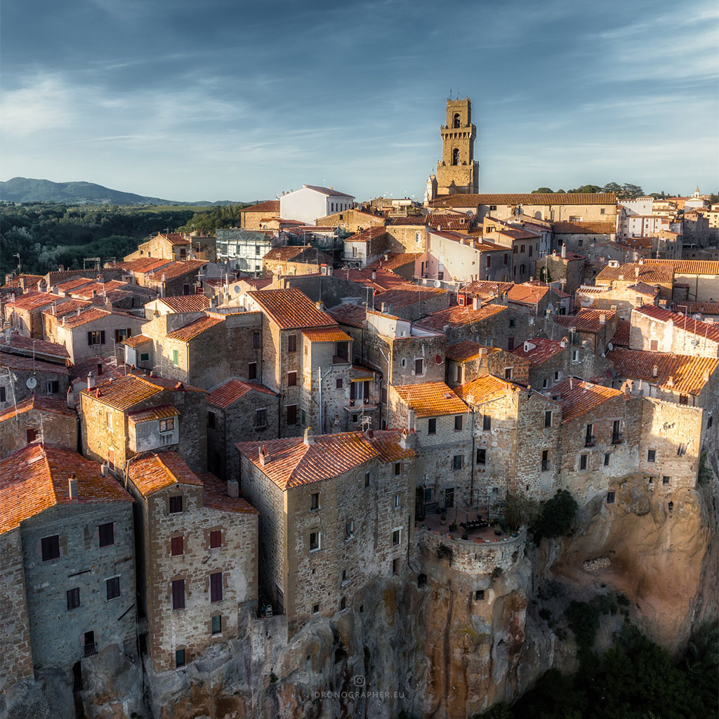 A medieval little town in Tuscany, Italy. Buildings with red roofs, made of bricks in an ancient way. A church tower is the towns center.
