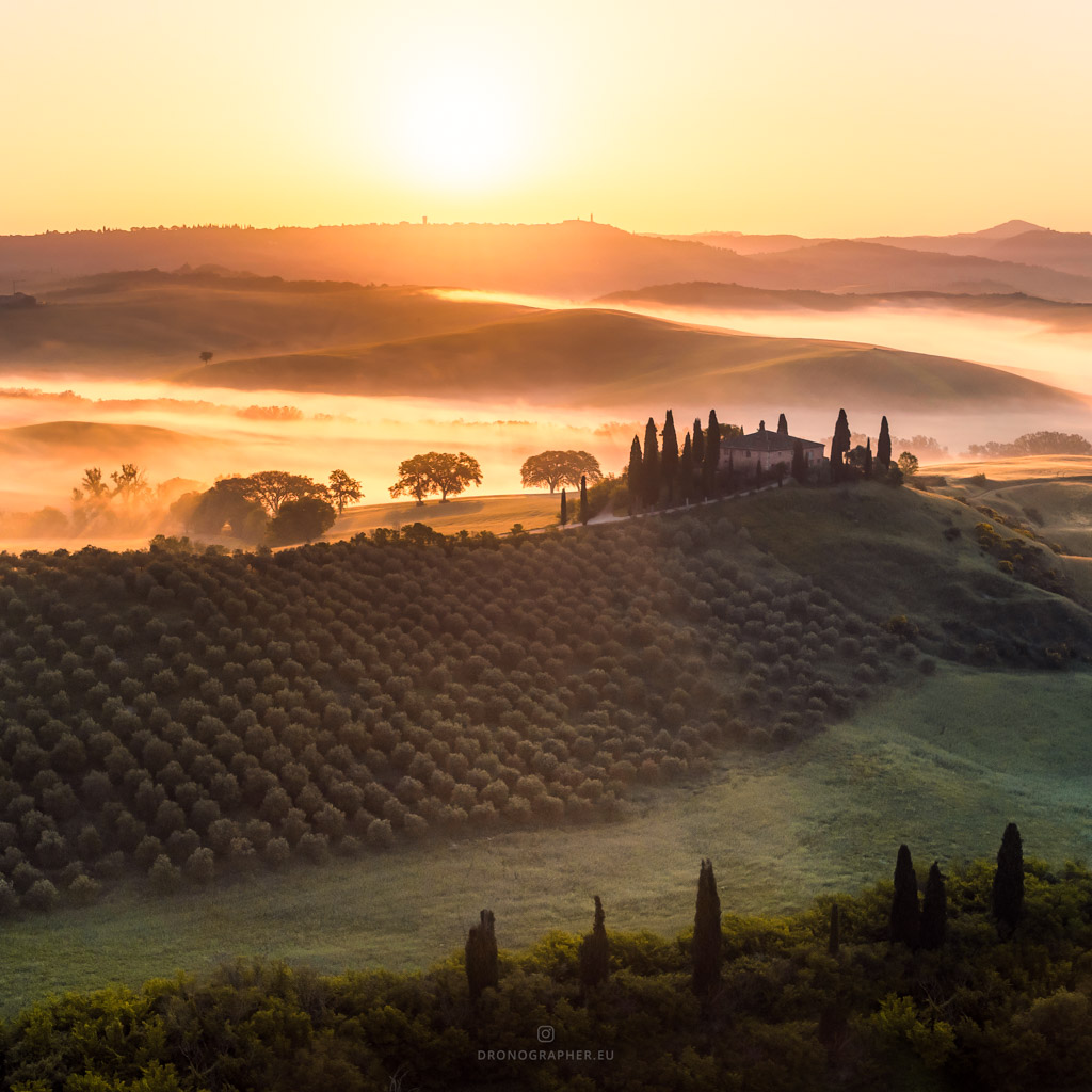 A villa in Tuscany during golden hour sunset. In the background are hills covered in mist.